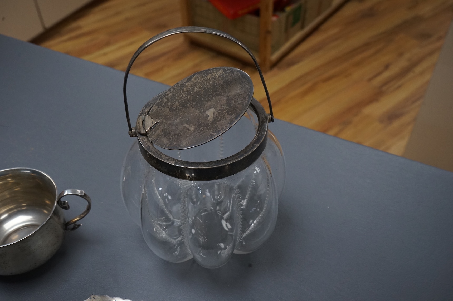 A late Victorian silver mounted lobed glass biscuit barrel by Hukin & Heath, with patent handle, London, 1899, height 14.4cm excluding the handle, together with a silver two handled condiment, a silver sugar bowl and a s